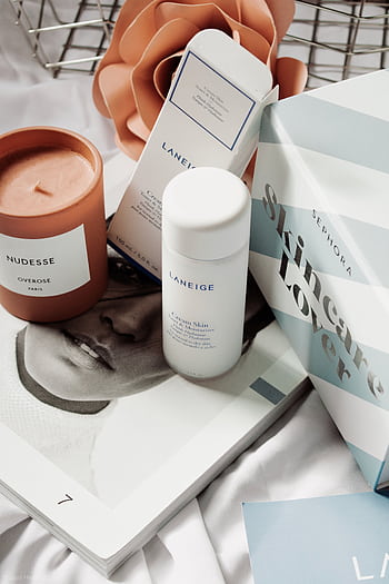 Skincare products and candle arranged in an elegant flat lay for beauty routines. HD phone wallpaper