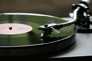 A close-up view of a rotating vinyl record on a vintage turntable player. HD wallpaper