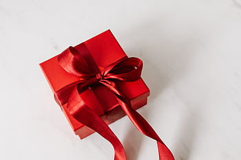 A red gift box with a satin ribbon, perfect for celebrations on a marble background. HD wallpaper