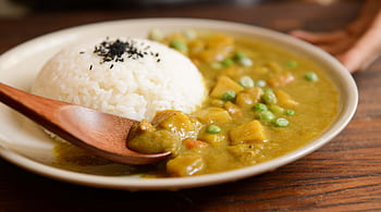 A delicious plate of creamy vegetable curry served with rice and a wooden spoon, perfect for a tasty meal. HD wallpaper
