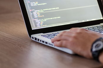 Person coding on a laptop with HTML code on screen, showcasing development work. HD wallpaper