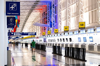 Wide view of Chicago airport terminal showcasing architecture and check-in counters. Flags and signages add vibrant detail. HD wallpaper