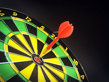 Close-up of a dart successfully hitting the bullseye on a bright dartboard, signifying victory. HD wallpaper