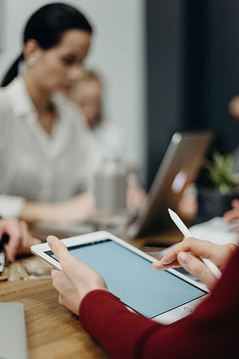 A focused team meeting showcasing digital collaboration with tablets and laptops in an office setting. HD phone wallpaper