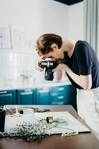 Woman taking of a still life setup with camera in a modern indoor setting. HD phone wallpaper