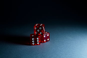 Three red transparent dice stacked on a dark surface, highlighting their reflective surfaces and dots. HD wallpaper