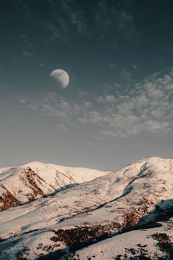 Serene snow-covered mountains under a crescent moonlit sky in winter, perfect for nature . HD phone wallpaper