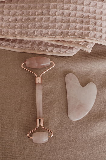 Flat lay of a rose quartz skincare tool set and towels for a wellness routine. HD phone wallpaper