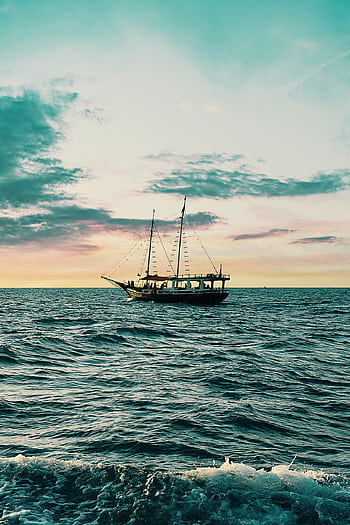 A majestic sailing ship navigates open waters at sunset, against a vibrant sky. HD phone wallpaper