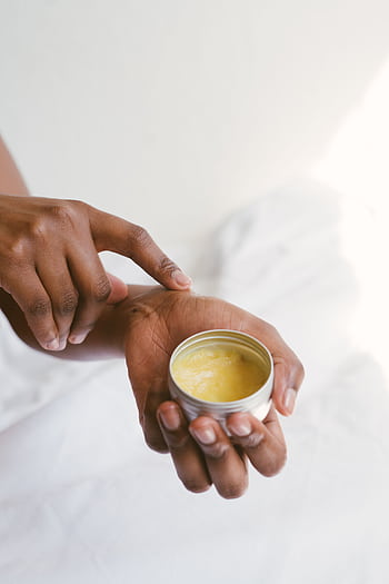 Close-up of a hand applying natural skincare cream, emphasizing self-care and holistic health. HD phone wallpaper