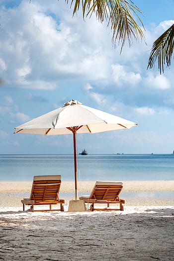 Idyllic beach scene with chairs and umbrella, perfect for a serene vacation setting. HD phone wallpaper