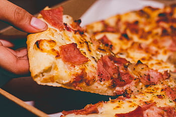 Close-up of a hand holding a delicious slice of pepperoni pizza. HD wallpaper