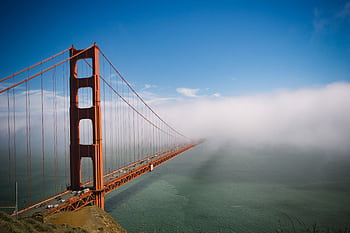 Stunning view of Golden Gate Bridge partially covered by fog with clear blue sky. HD wallpaper