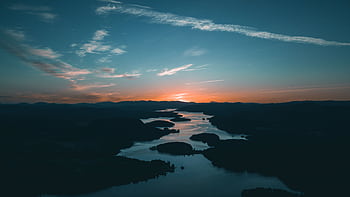 A breathtaking aerial shot showcasing a calm river winding through hills at sunset, with a vivid sky. HD wallpaper