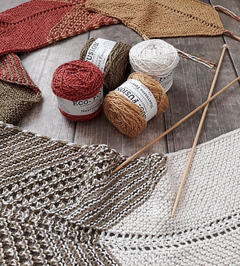 Colorful yarns and knitting needles for creating handmade crafts on a wooden surface. HD phone wallpaper