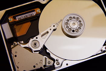 Detailed close-up of a hard disk drive showing the actuator arm and data platters. HD wallpaper