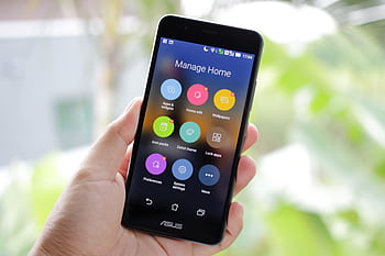 A hand holding a smart displaying home management apps on the screen. HD wallpaper