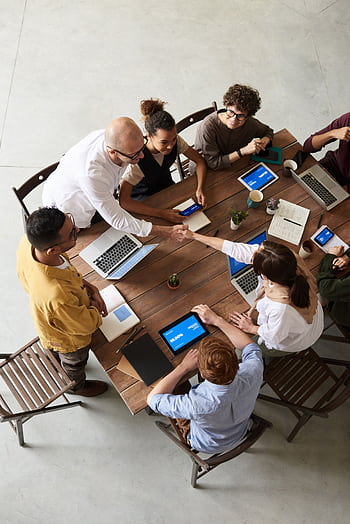 Overhead shot of a diverse team collaborating in a modern office meeting. HD phone wallpaper