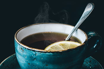 Close-up of aromatic steaming lemon herbal tea served in a ceramic cup with saucer. HD wallpaper