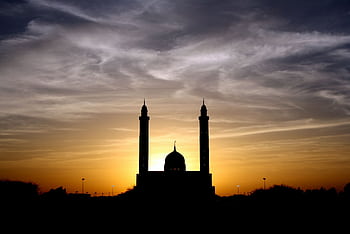 Beautiful silhouette of a mosque against a vibrant sunset sky, highlighting its architectural elegance. HD wallpaper