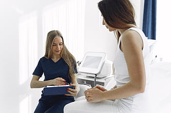 Nurse helping a female patient during a check-up in a modern, bright clinic setting. HD wallpaper