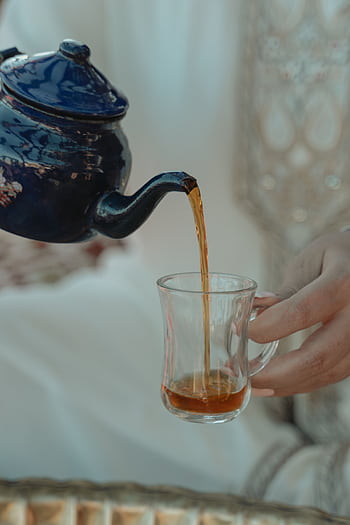 Elegant tea pouring from a teapot into a glass, highlighting Middle Eastern culture and tradition. HD phone wallpaper
