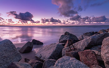 Beautiful rocky seashore at sunset with serene ocean waves and colorful sky. HD wallpaper