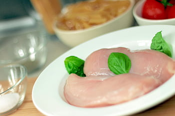 Close-up of raw chicken breasts on a plate with basil leaves, ideal for culinary themes. HD wallpaper