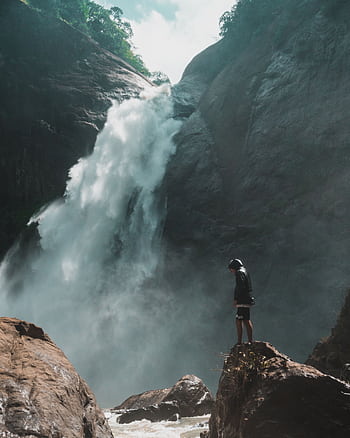 A man standing near a breathtaking waterfall in Badulla, Sri Lanka, showcasing nature's beauty and adventure. HD phone wallpaper