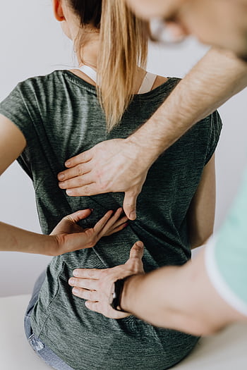 Chiropractor performs manual adjustment on a patient's back to alleviate discomfort and improve posture. HD phone wallpaper