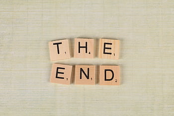 Close-up of Scrabble tiles spelling 'The End' on a simple wooden background for creative concepts. HD wallpaper
