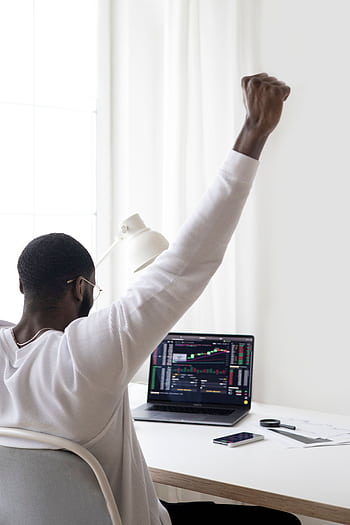 A man celebrates a successful stock market trade while sitting at his desk. HD phone wallpaper