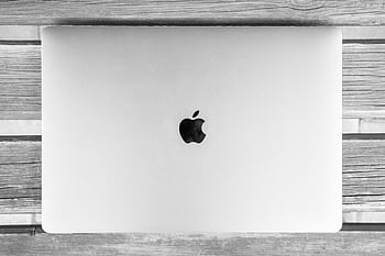 Black and white of a closed laptop on a rustic wooden table. Minimal and classic design. HD wallpaper
