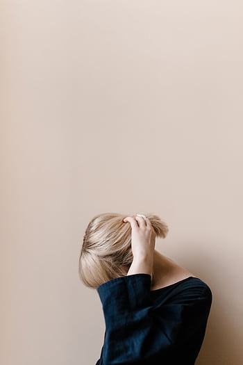 A serene portrait of a young woman with blonde hair, showcasing minimalist fashion and a neutral background. HD phone wallpaper
