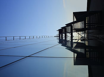 A striking glass skyscraper reflecting blue skies, showcasing modern architecture's elegance. HD wallpaper