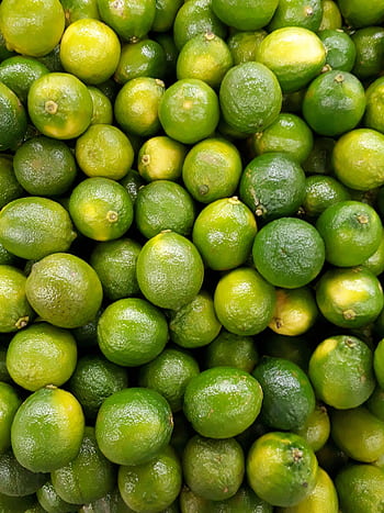 A vibrant collection of fresh green limes showcasing natural abundance. HD phone wallpaper