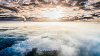 Dramatic aerial view of a cloudy landscape with sunlight breaking through the sky at sunset. HD wallpaper
