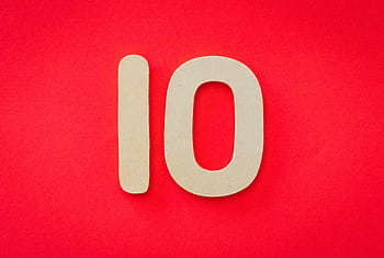 Wooden number 10 on a vibrant red background, ideal for educational and creative projects. HD wallpaper