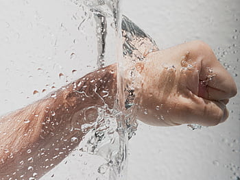 Dynamic showing a clenched hand submerged in a splash of clear water, emphasizing motion and hygiene. HD wallpaper