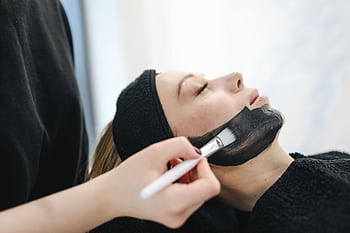 Close-up of a woman enjoying a relaxing charcoal facial treatment in a spa. HD wallpaper
