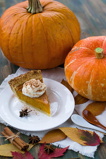 Slice of pumpkin pie with whipped cream, surrounded by pumpkins and autumn leaves, perfect for fall celebrations. HD phone wallpaper