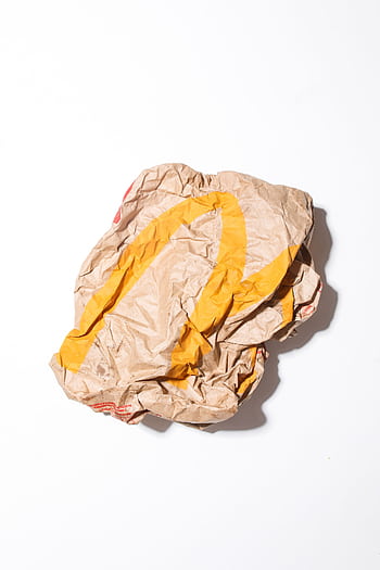 Crumpled fast food paper bag showcasing consumer waste and environmental concerns. HD phone wallpaper