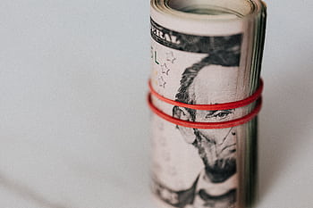Close-up of a roll of US dollars wrapped with a red rubber band focusing on financial abundance. HD wallpaper