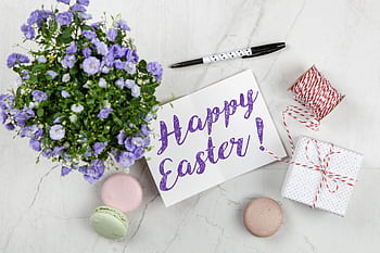 Easter greeting card with flowers, macarons, and gift on a marble surface. HD wallpaper