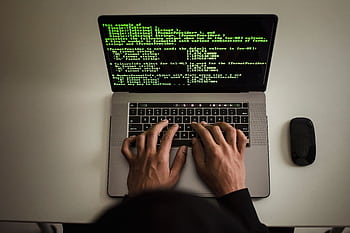 Hands typing code on a laptop with programming text on screen, indoors. HD wallpaper