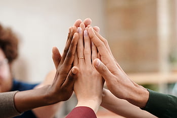 Close-up of diverse group hands high-fiving symbolizing teamwork and unity. HD wallpaper