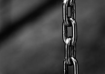 Detailed close-up of a strong shiny metallic chain link against a blurred background, emphasizing security. HD wallpaper