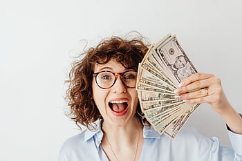 Caucasian woman with curly hair delights in holding US dollars against a white background. HD wallpaper
