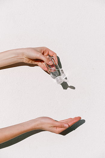 Person applying hand sanitizer against white backdrop, emphasizing hygiene and protection. HD phone wallpaper