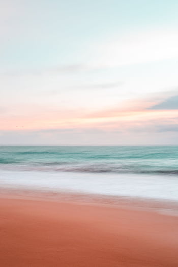 Stunning sunset view over a peaceful beach with gentle waves and colorful sky. HD phone wallpaper